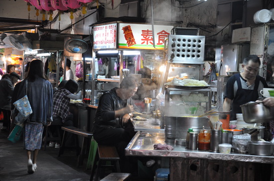 小吃攤的組成元素是食物、老闆、幫手,沒有商品式的包裝,反映的是貼近民生需求的庶民生活。